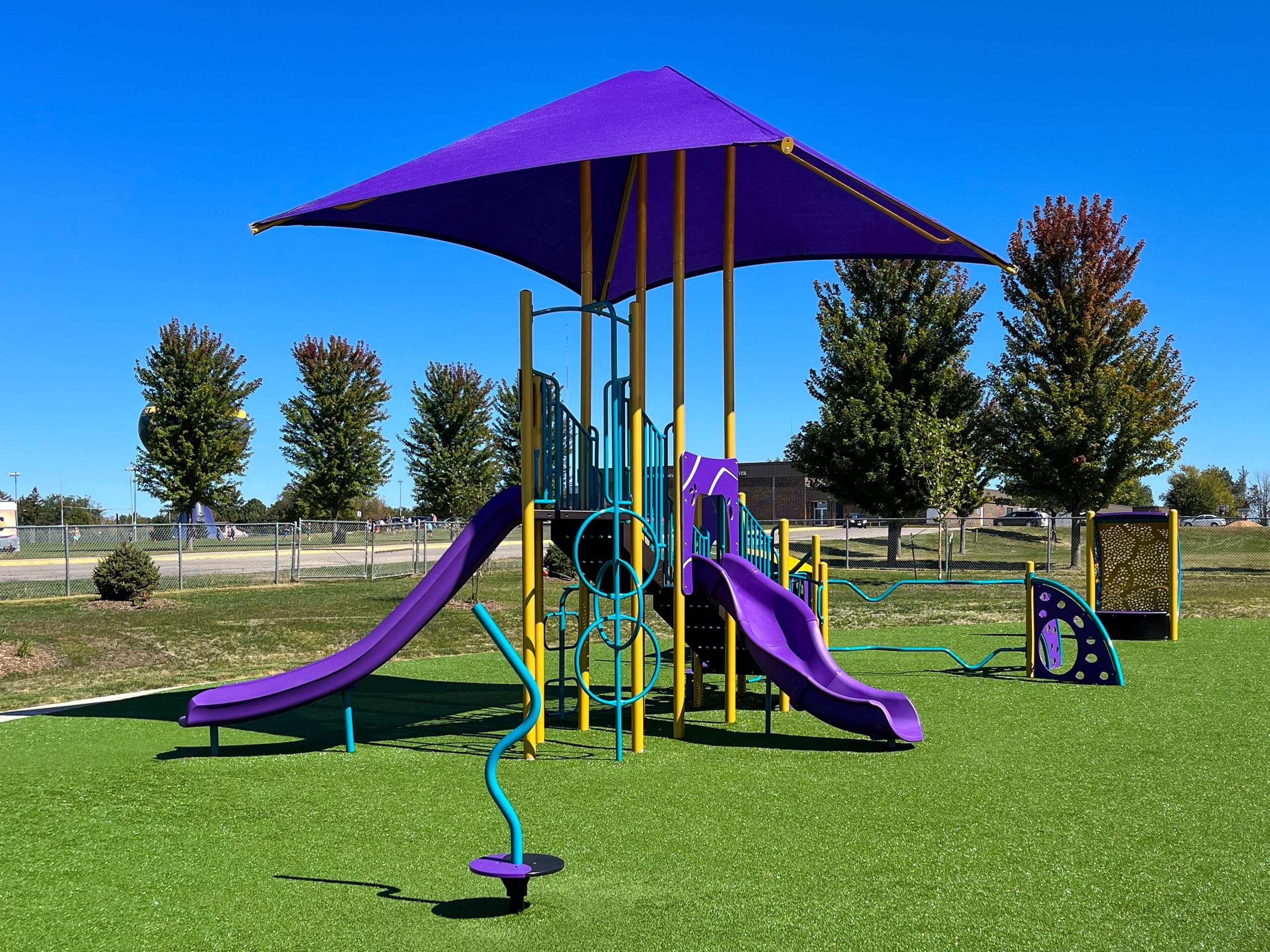 Outdoor play area with a slide, climbing features on synthetic turf.