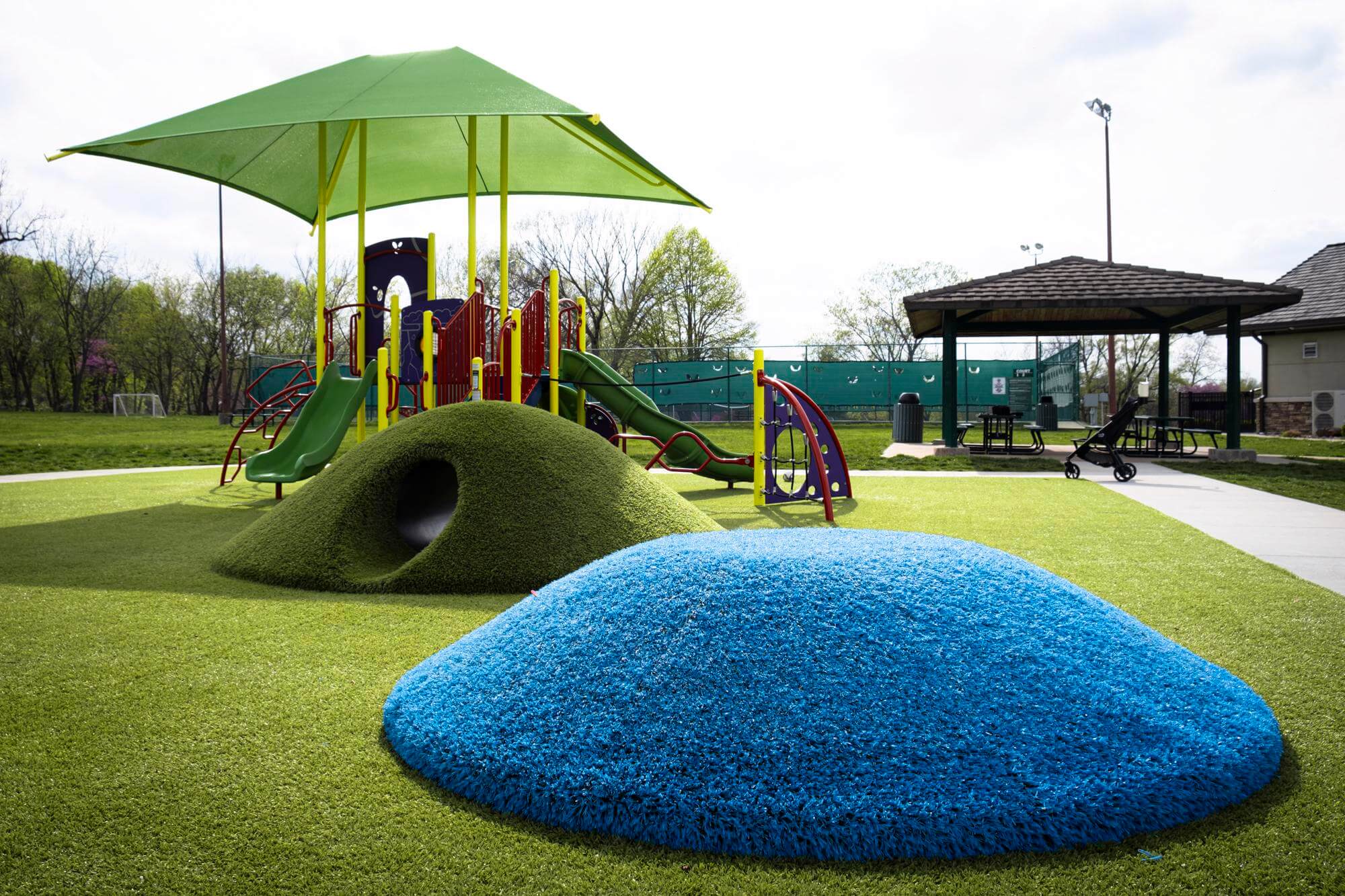 Playground with synthetic grass and a blue play mound.