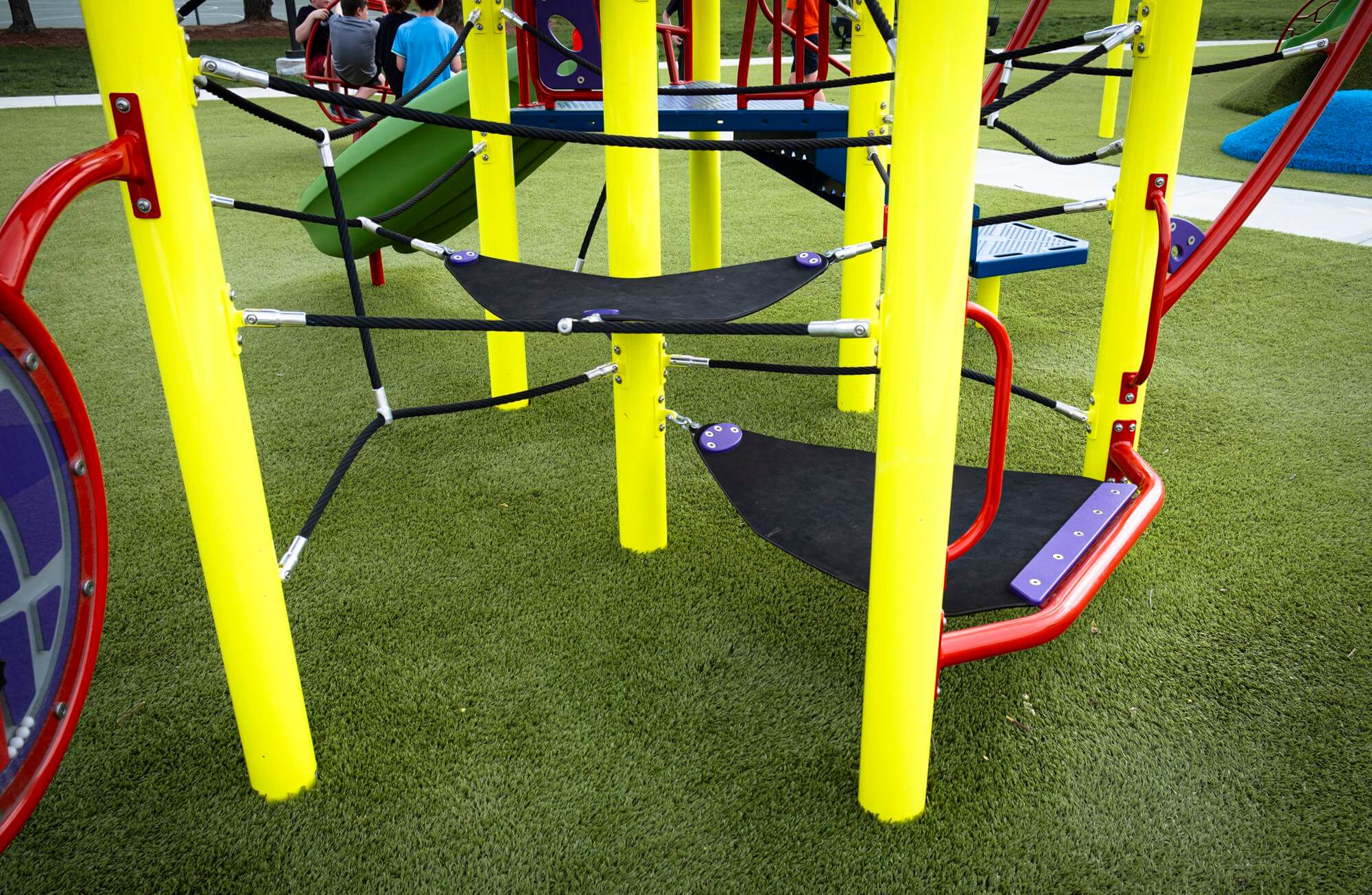 Close up shot of colorful playground equipment on vibrant green turf.