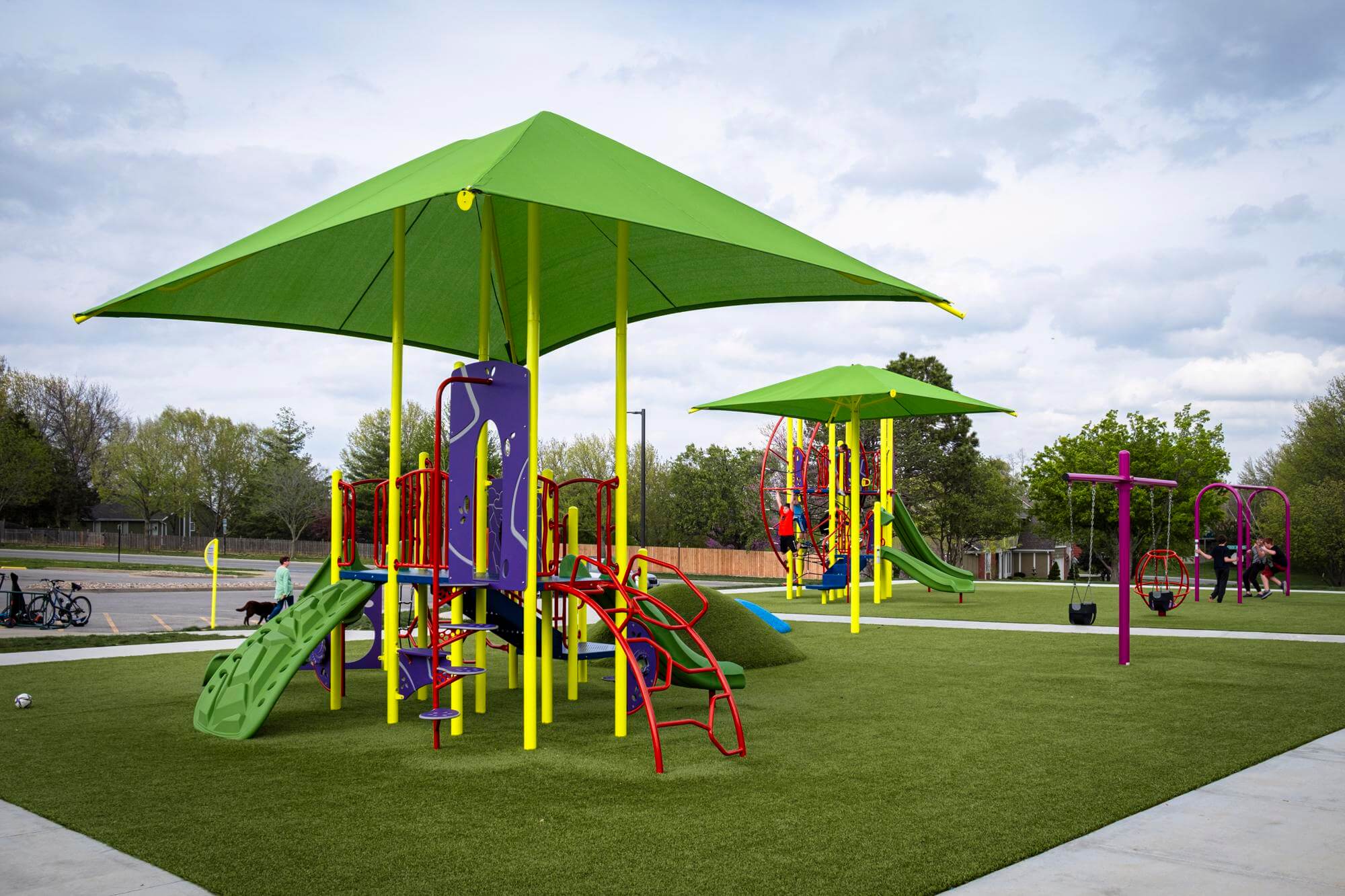 Playground with artificial turf and a variety of climbing structures.