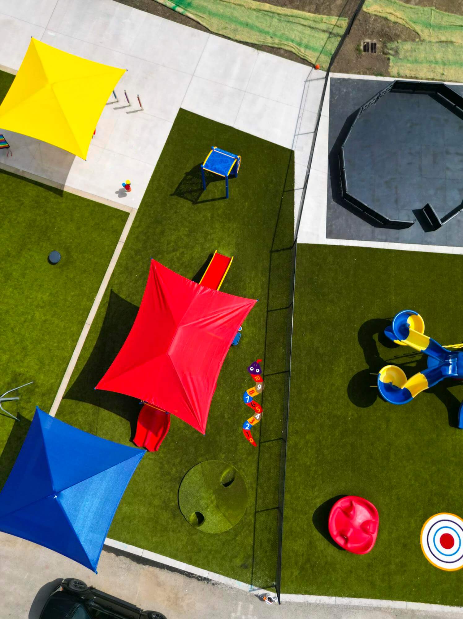 Another aerial perspective of the playground showcasing blue and red sunshades, a climbing structure, and a play area.