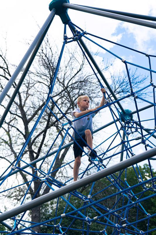 Young boy climbing a rope structure.