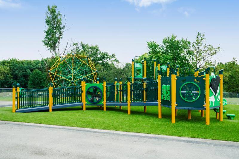 Wide angle of vibrant yellow and green playground on artificial green turf